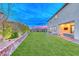 Expansive backyard featuring a lush lawn, brick retaining wall, and covered patio with comfortable seating at 940 Riverlawn Pl, Las Vegas, NV 89138