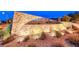 Beautiful stone signage for the Caledonia community with desert landscaping and subtle lighting at 940 Riverlawn Pl, Las Vegas, NV 89138