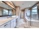 Bright main bathroom featuring double sinks, large mirror, soaking tub, and a glass-enclosed shower at 940 Riverlawn Pl, Las Vegas, NV 89138