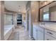 Serene bathroom featuring tile flooring, glass shower, tub and convenient access to the vanity and main bedroom at 940 Riverlawn Pl, Las Vegas, NV 89138