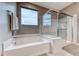 Bright bathroom featuring a tub, glass-enclosed shower, neutral color palette, and a view to the neighborhood at 940 Riverlawn Pl, Las Vegas, NV 89138