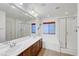 Bright bathroom featuring double sinks, a large mirror, and a glass-enclosed shower and bath at 10247 Gladstone Peak St, Las Vegas, NV 89166