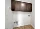 Well-lit laundry room featuring abundant overhead cabinet storage and tiled floors at 10247 Gladstone Peak St, Las Vegas, NV 89166
