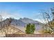 View of snow-capped mountains from behind a brick wall with rooflines and foliage at 10247 Gladstone Peak St, Las Vegas, NV 89166