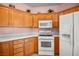 Bright kitchen featuring oak cabinets, white appliances, and tile floors at 1184 Warm Canyon Way, Las Vegas, NV 89123