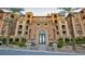 Elegant condo building entrance with lush landscaping, decorative iron doors, and palm trees at 15 Via Mantova # 104, Henderson, NV 89011