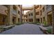 Picturesque courtyard with brick paving, benches, and lush landscaping, offering a tranquil outdoor space at 15 Via Mantova # 104, Henderson, NV 89011