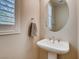Bathroom features a pedestal sink, oval mirror, neutral color palette, and a window with stylish shutters at 1973 Ardilea St, Las Vegas, NV 89135