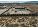An aerial shot of a property shows a pool, outbuildings, and grass inside a fenced perimeter, set in a desert landscape at 2330 Deadwood St, Pahrump, NV 89048