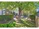 Charming backyard featuring a mature shade tree, brick patio, manicured hedges and an inviting seating area at 3111 Coachlight Cir, Las Vegas, NV 89117