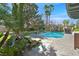 Inviting backyard oasis with a large pool, rock waterfall, tropical landscaping, and comfortable lounge chairs at 3111 Coachlight Cir, Las Vegas, NV 89117
