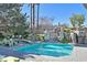 Backyard with pool, rock waterfall, mature trees, and sun loungers; ideal for relaxation and outdoor enjoyment at 3111 Coachlight Cir, Las Vegas, NV 89117