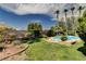 A landscaped backyard featuring a pool, spa, mature trees, and green grass at 6513 Echo Crest Ave, Las Vegas, NV 89130