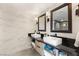 Modern bathroom with double sinks, framed mirrors, elegant fixtures, and marble-look walls at 6975 Darby Ave, Las Vegas, NV 89117