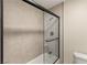 Modern bathroom features a black framed sliding shower door and neutral colored wall tiles at 6975 Darby Ave, Las Vegas, NV 89117