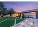 Inviting front yard with manicured lawn, decorative stonework, and warm exterior lighting at twilight at 6975 Darby Ave, Las Vegas, NV 89117