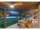 Covered patio with a dining table, lights, and a view of the pool and putting green in the backyard at 6975 Darby Ave, Las Vegas, NV 89117