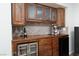 Dark wood bar area features upper cabinets with glass doors and a wine refrigerator at 7317 Bosky Springs St, Las Vegas, NV 89131