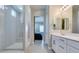 Modern bathroom featuring a sleek shower, vanity, and large mirror, with a glimpse into the primary bedroom at 792 Drammatico Pl, Henderson, NV 89011