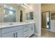 Modern bathroom with dual sinks, vanity with drawers, large mirrors, and access to a walk-in closet at 792 Drammatico Pl, Henderson, NV 89011