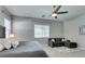 Bright primary bedroom boasts a ceiling fan, large window, neutral color scheme, and cozy seating area at 792 Drammatico Pl, Henderson, NV 89011