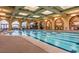 A beautiful indoor pool with lane markers, decorative arches, and artwork in a well-lit, elegant space at 10580 Riva Grande Ct, Las Vegas, NV 89135