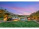 Scenic backyard view with lush green grass, mountain backdrop, and an illuminated outdoor entertaining space at 11680 Evergreen Creek Ln, Las Vegas, NV 89135