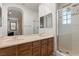 Bathroom featuring double sinks, wooden cabinets, and a glass-enclosed shower with tile surround at 11680 Evergreen Creek Ln, Las Vegas, NV 89135