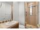 Cozy bathroom featuring a shower with glass door and decorative tile and a single sink vanity with tiled countertop at 11680 Evergreen Creek Ln, Las Vegas, NV 89135