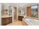 Elegant bathroom with a soaking tub, walk-in shower, dual vanities, and scenic outdoor views at 11680 Evergreen Creek Ln, Las Vegas, NV 89135