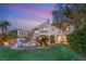 Two-story home exterior with landscaped yard, lush greenery, outdoor lighting, and water feature at 11680 Evergreen Creek Ln, Las Vegas, NV 89135
