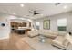 Spacious living room featuring a modern ceiling fan, plush sectional, and seamless flow into the kitchen at 11680 Evergreen Creek Ln, Las Vegas, NV 89135
