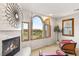 Main bedroom with fireplace, seating, and windows offering views of the green landscape at 11680 Evergreen Creek Ln, Las Vegas, NV 89135