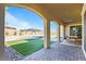 Covered patio overlooks backyard, featuring a pool, artificial turf, stone accents and outdoor dining area at 11834 Albissola Ave, Las Vegas, NV 89138