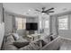 Bright living room featuring neutral tones, a comfortable grey sectional, a modern ceiling fan, and wood-look flooring at 140 Rolling Cove Ave, Henderson, NV 89011