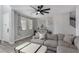 Bright living room featuring neutral tones, a comfortable grey sectional, a modern ceiling fan, and wood-look flooring at 140 Rolling Cove Ave, Henderson, NV 89011