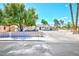 The home features a spacious driveway and decorative concrete fencing, complemented by mature trees at 1700 Ivanhoe Way, Las Vegas, NV 89102