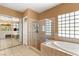 A tiled bathroom features a glass shower, a soaking tub, and a mirrored closet at 215 Great Gable Dr, Las Vegas, NV 89183