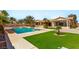 Spacious backyard features a sparkling pool, well-manicured lawn, and mature palm trees at 215 Great Gable Dr, Las Vegas, NV 89183