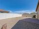A spacious backyard with gravel, brick patio, and a white fence, perfect for outdoor activities and relaxation at 4016 Balsam Mountain St, Las Vegas, NV 89129