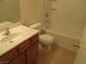 A bathroom with a tub-shower, wooden cabinets and a white toilet and sink at 5481 Railroad River Ave, Las Vegas, NV 89139