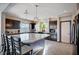 Open kitchen with seating at the island, dark cabinets, granite counters, and modern pendant lights at 5946 Ancient Peaks Ave, Las Vegas, NV 89141