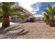 Home featuring a three-car garage, gravel front yard, palm trees, and wrought iron driveway gate at 6915 Cedar Basin Ave, Las Vegas, NV 89142