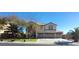 Two-story home with a three-car garage, large windows, mature trees, and a well-manicured lawn at 6915 Cedar Basin Ave, Las Vegas, NV 89142