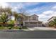 Two-story home with a three-car garage, manicured lawn, mature trees, and neutral color scheme at 6915 Cedar Basin Ave, Las Vegas, NV 89142