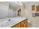 Bathroom featuring double sinks with framed mirror, walk-in shower with curtain, and standard toilet at 7425 Enchanted Hills Ct, Las Vegas, NV 89129