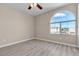 Bright bedroom featuring modern gray wood floors, neutral walls, a ceiling fan, and a large arched window at 7425 Enchanted Hills Ct, Las Vegas, NV 89129