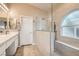 Modern bathroom features tiled floors, dual sinks and a glass-enclosed shower with built-in bench at 7690 Blue Whirlpool St, Las Vegas, NV 89131