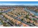 Stunning aerial view of a Primary-planned community featuring terra cotta-roofed homes, lush landscaping, and a vast network of waterways at 8132 Bay Harbor Dr, Las Vegas, NV 89128