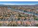 Expansive aerial view of a neighborhood featuring homes with terra cotta roofs, desert landscaping, and a picturesque waterway at 8132 Bay Harbor Dr, Las Vegas, NV 89128